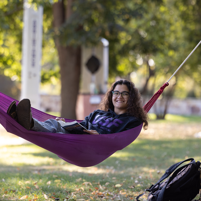 student reading in a hammock on campus