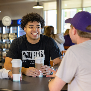 two students talking with coffee